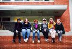 Antioch College students sit together on a red brick wall