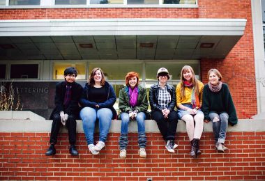 Antioch College students sit together on a red brick wall