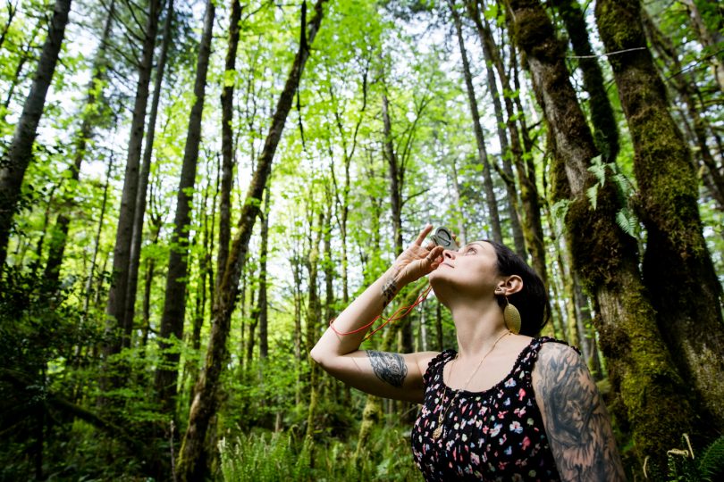 A student measures the trees in the forest on campus.