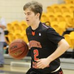 A Rhodes College varsity men's player dribbles the basketball