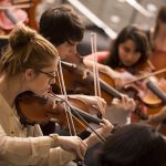 Southwestern University orchestra students play violins together