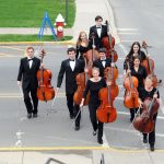 Juniata orchestra students walk across campus carrying their instruments