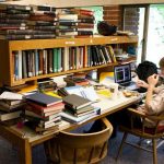 A Reed College student studies among stacks of books