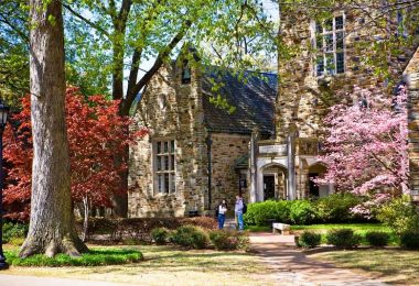 Students stand in front of a Rhodes College campus building on a fall day