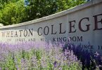 Flowers bloom in front of the Wheaton College campus sign