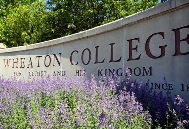 Flowers bloom in front of the Wheaton College campus sign