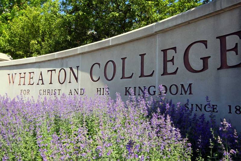 Flowers bloom in front of the Wheaton College campus sign