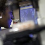 Cornell College student looks into a monitor