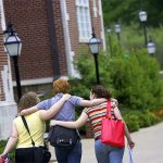 Hendrix College students walk arm in arm across campus