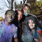 Smiling students covered in colored powder during Holi, a festival of colors