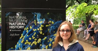 St. Olaf student stands in front of the Smithsonian Natural History Museum sign