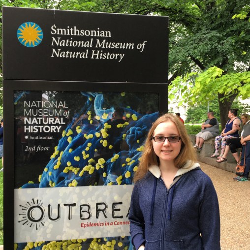 St. Olaf student stands in front of the Smithsonian Natural History Museum sign