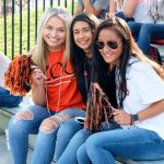 Three students cheer on the Kalamazoo College football team at Homecoming